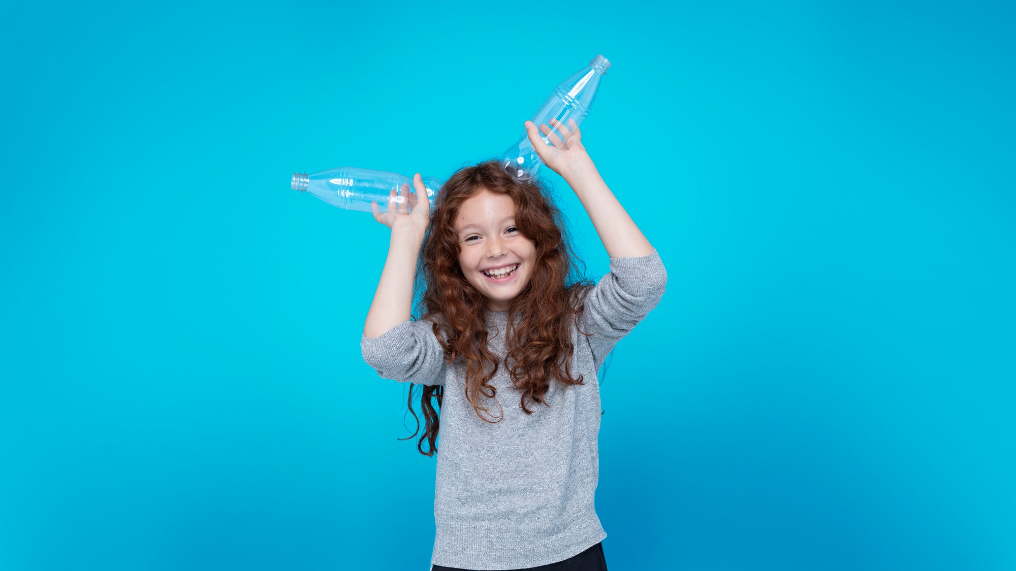 Girl in blue background with 2 bottles