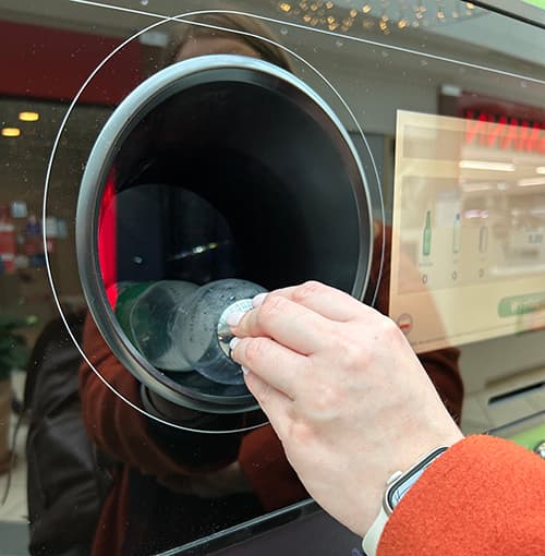 person inserting a plastic bottle into a TOMRA reverse vending machine 